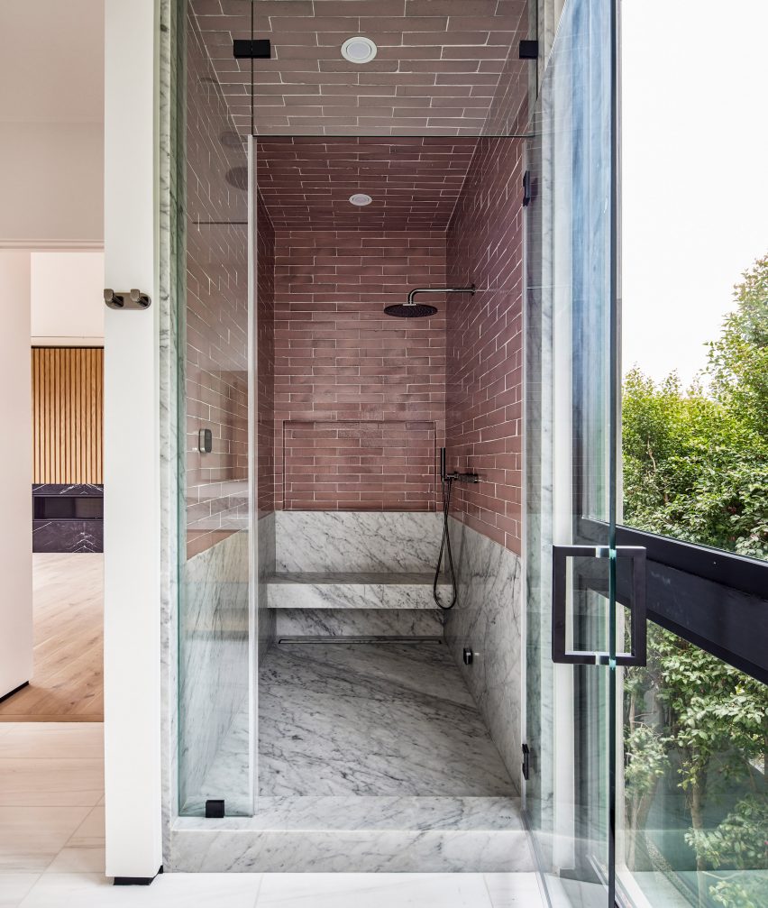 Shower wet room with marble floor and red brick-patterned wall tiles