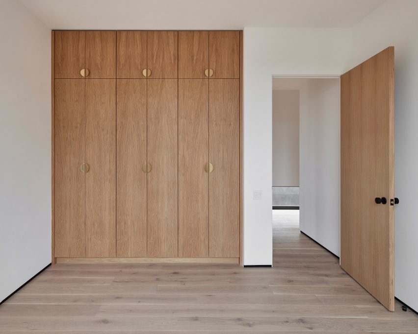 Room with white walls, timber flooring and built-in timber wardrobes
