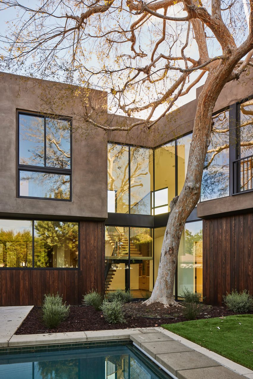 Stucco and ash-clad home with a swimming pool and elm tree in front