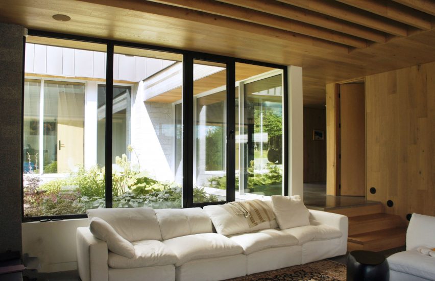 A living room with a white sofa and floor-to-ceiling windows looking onto a courtyard