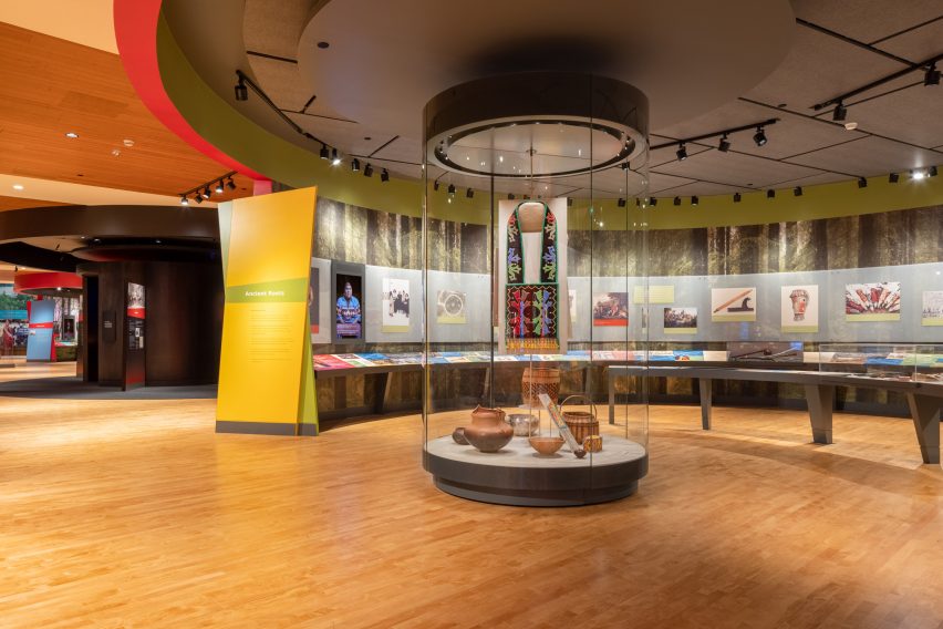 Interior museum gallery space with curved wall display and cylindrical glass display