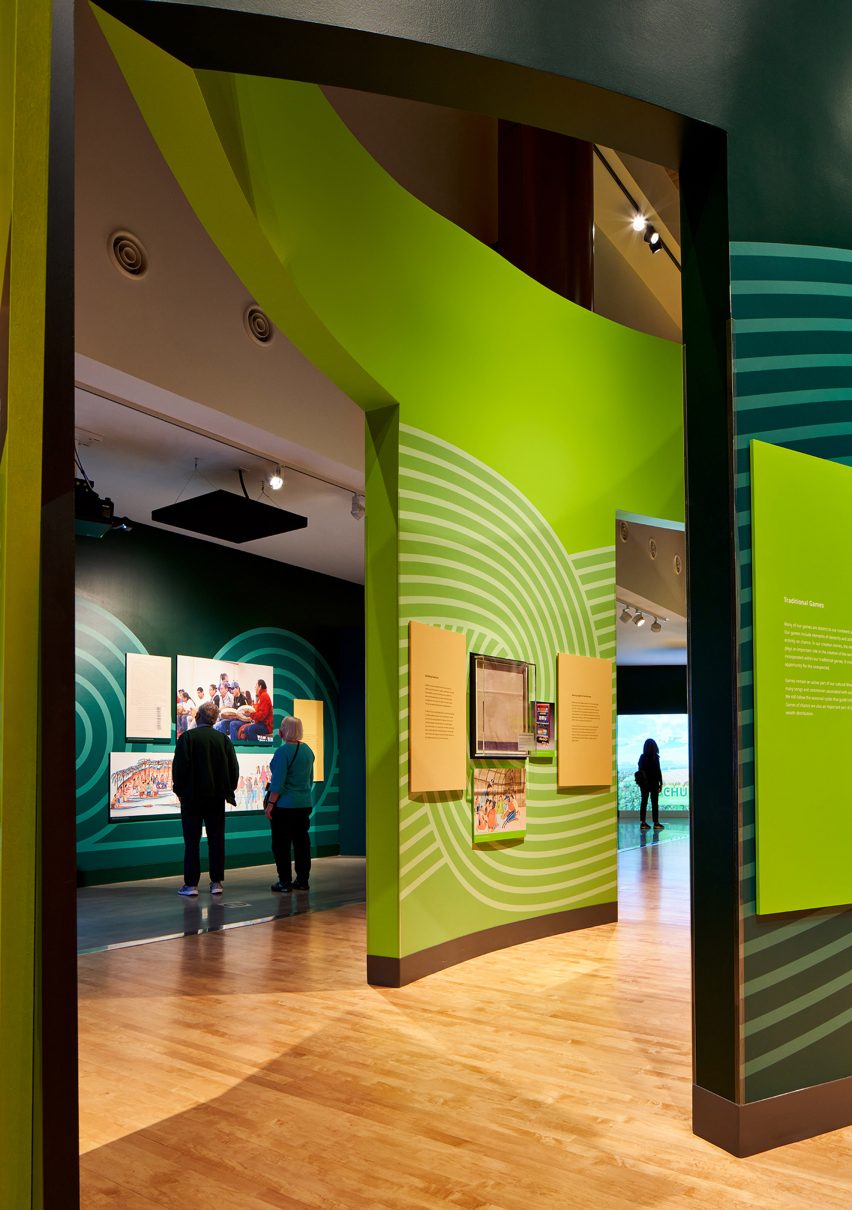 Interior museum gallery space with wood flooring and green wall partition displays