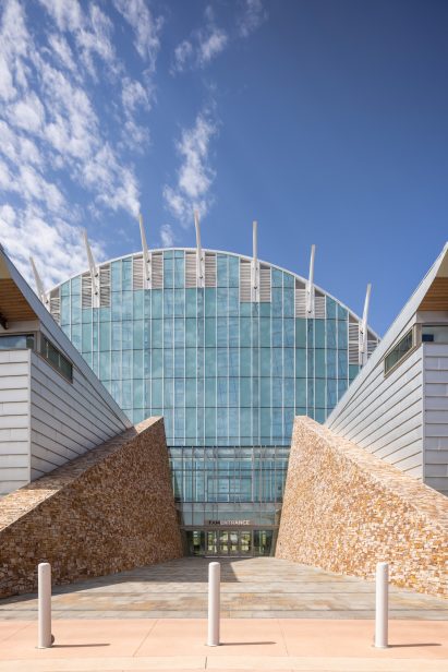 A paved opening between two buildings with leading to a large arched glass building