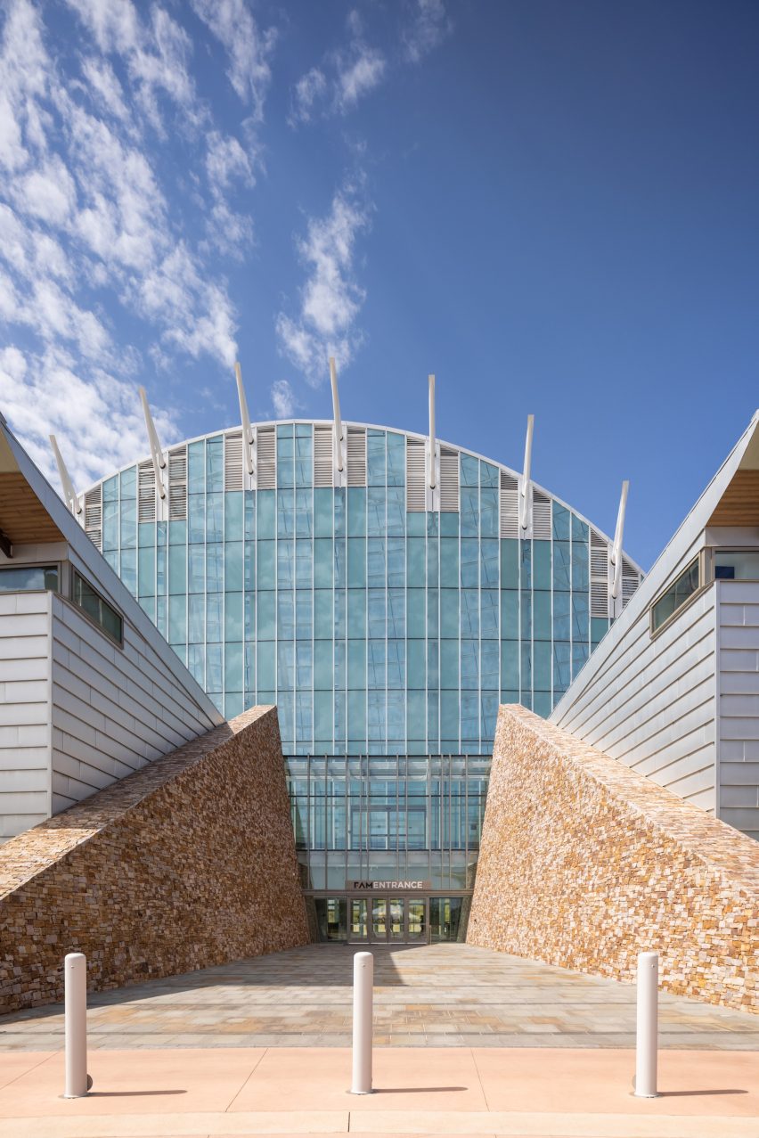 A paved opening between two buildings with leading to a large arched glass building