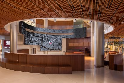 Interior museum space with circular opening in the ceiling, circular steel columns and curved bench seating