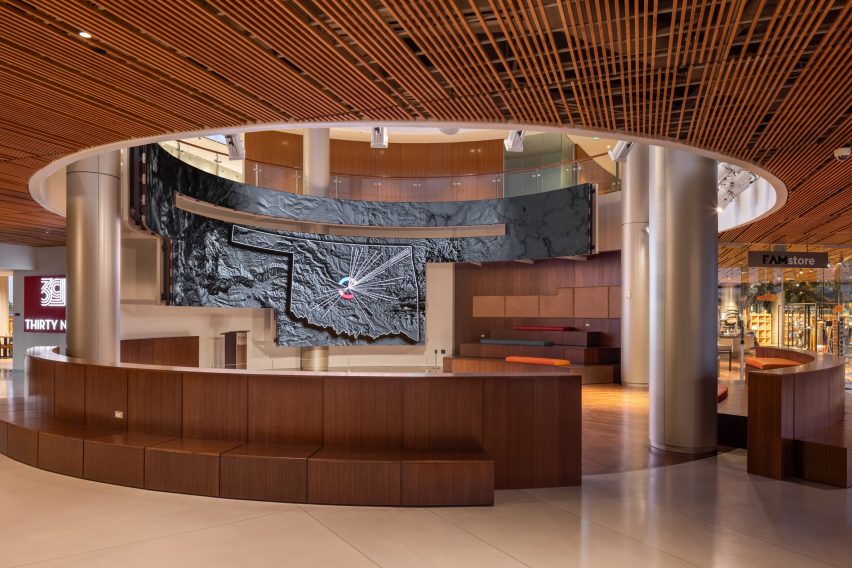 Interior museum space with circular opening in the ceiling, circular steel columns and curved bench seating
