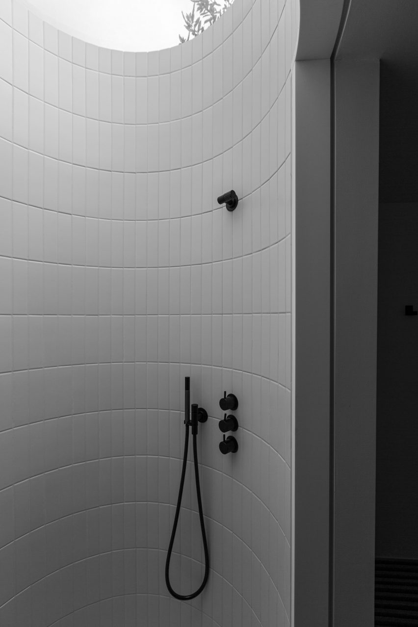 Circular white-tiled shower with a skylight and black fixtures