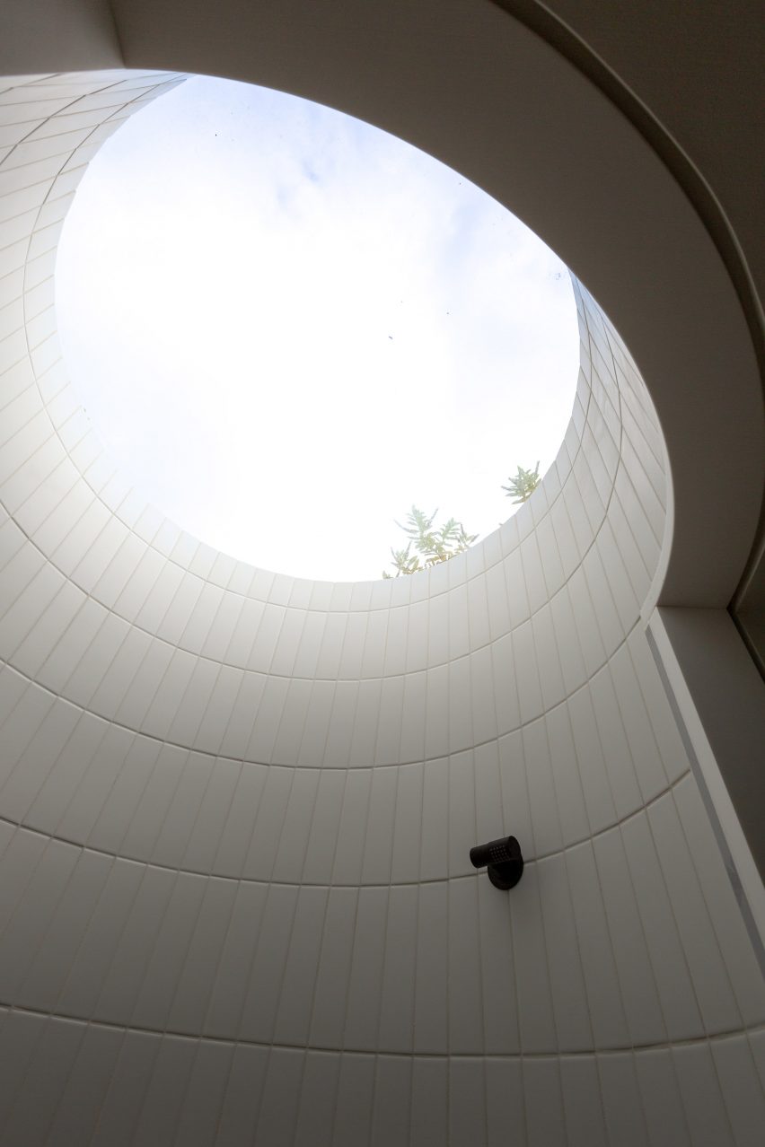 Circular white-tiled shower with a skylight and black fixtures
