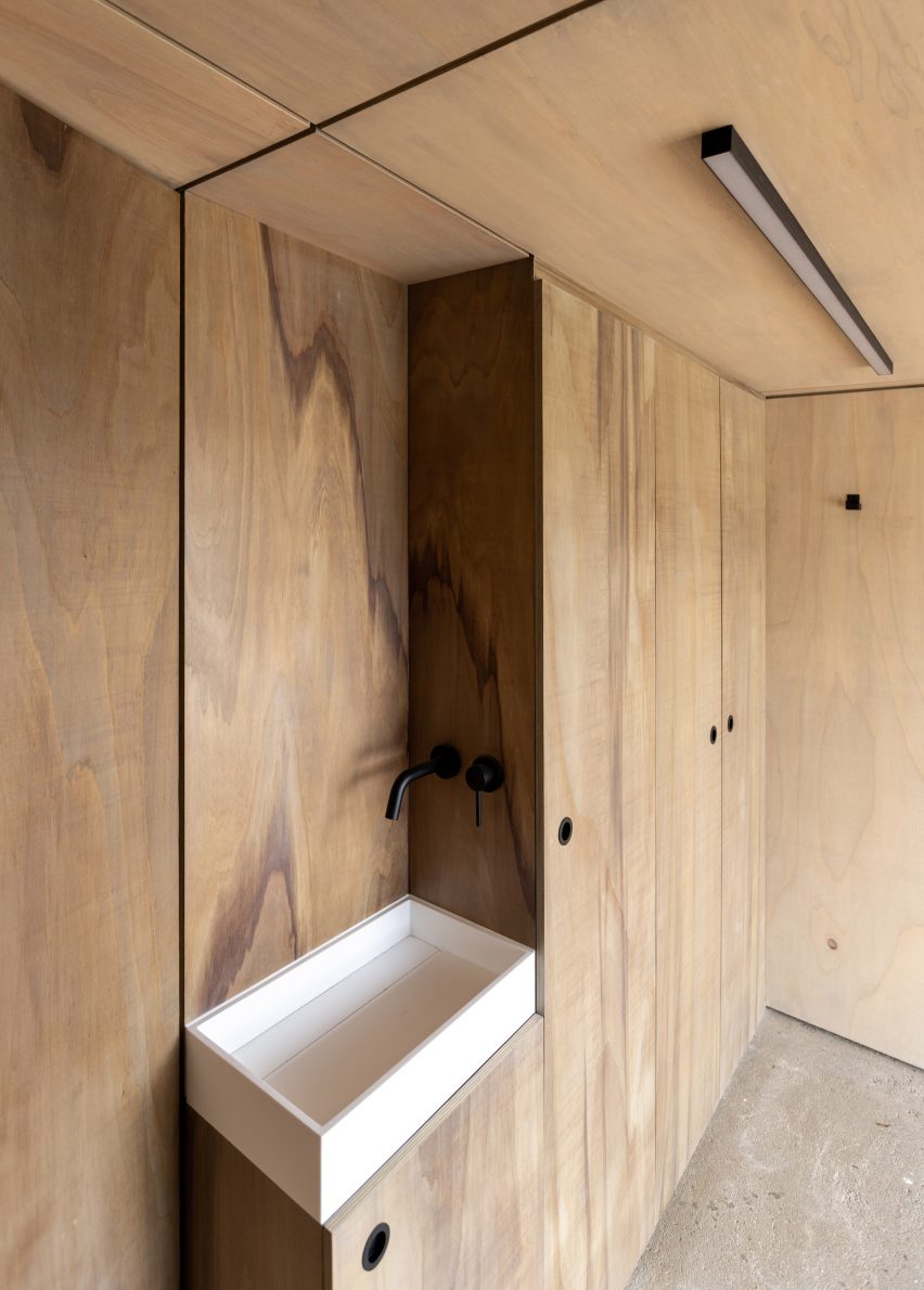 Interior of a pool house with built-in wooden storage and white sink