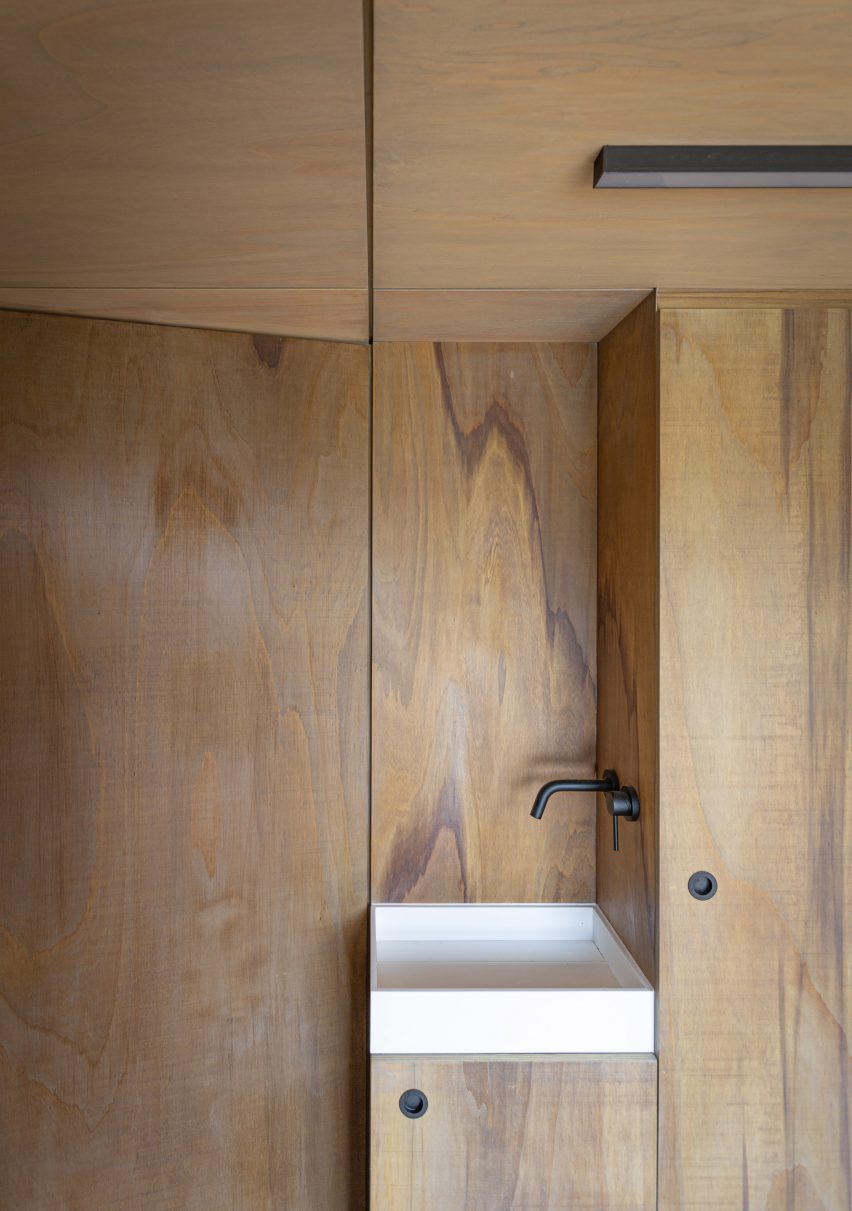 Interior of a pool house with built-in wooden storage and white sink