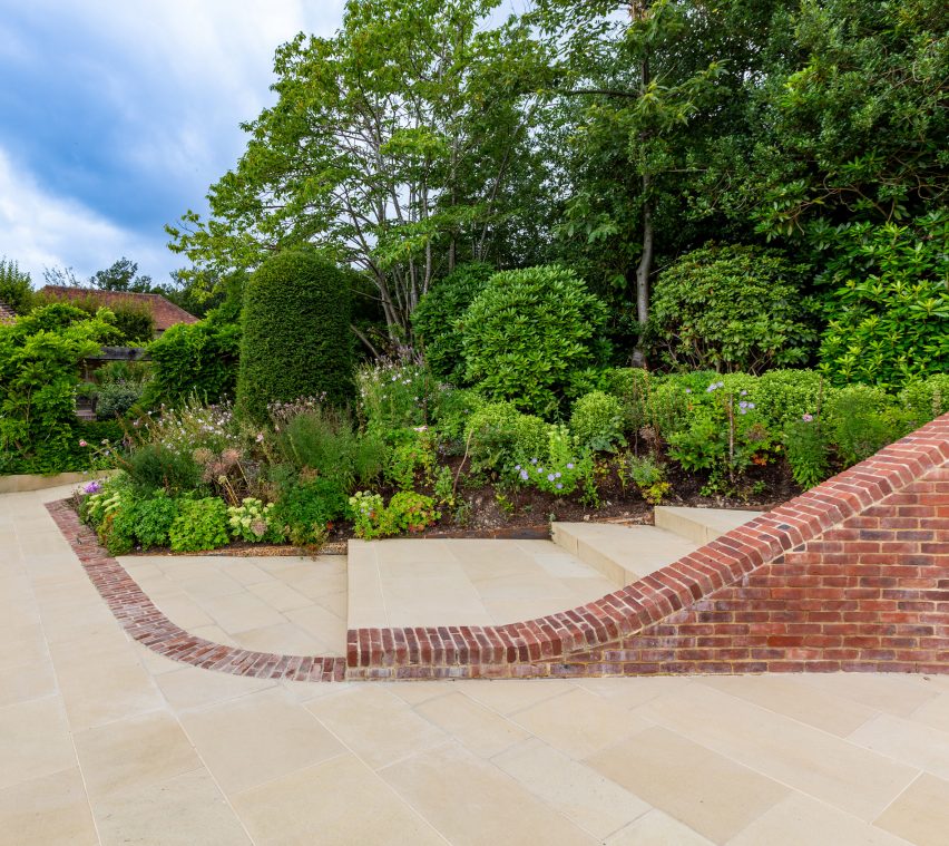 Planted garden with wide paved steps and a curved brick wall