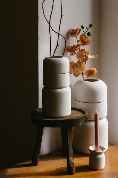 Three stoneware urns with flowers and candle