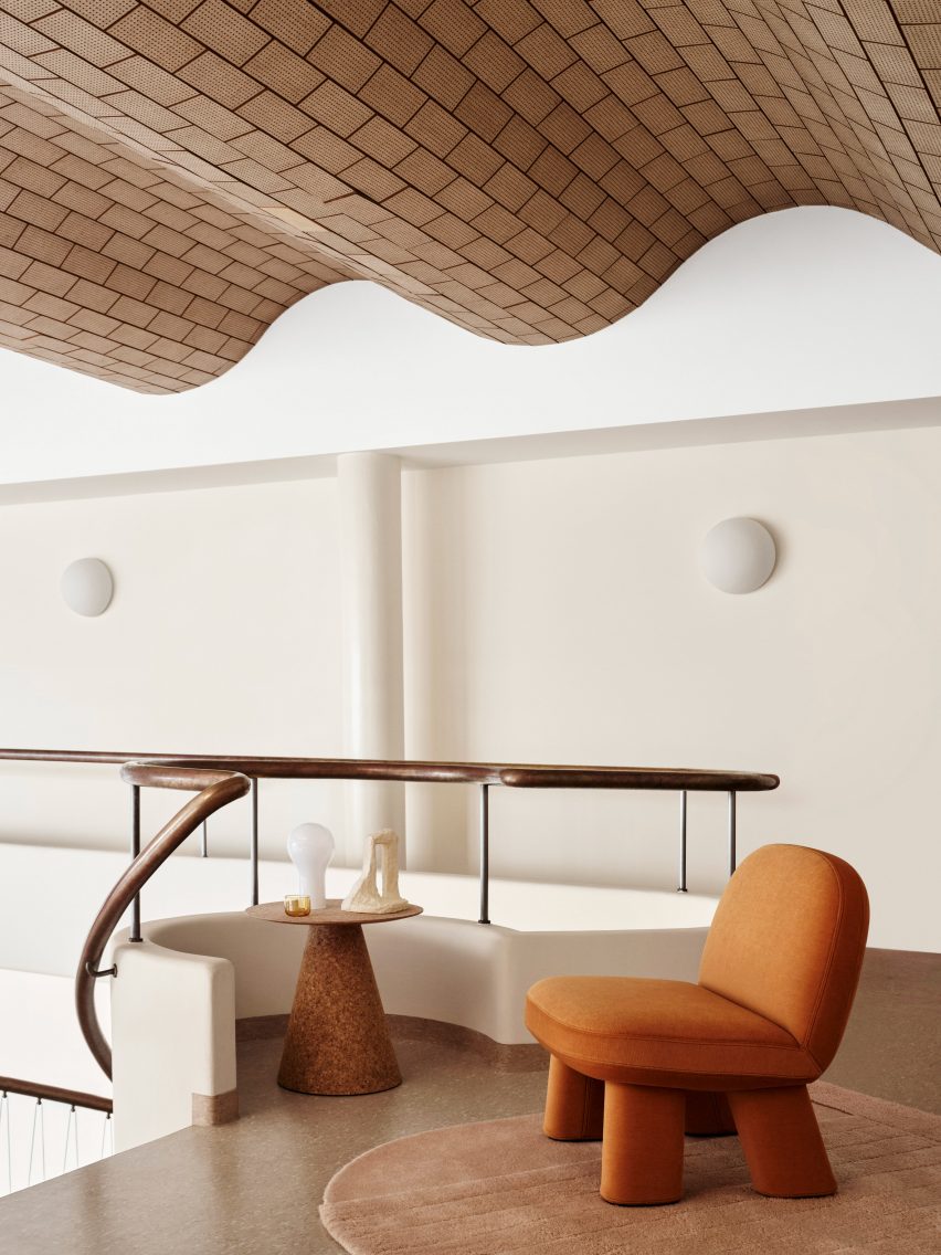 Orange rounded chair on mezzanine below wavy ceiling