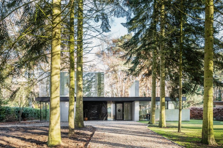 Two-storey home in a forest with a glazed ground floor and mirror-clad upper floor
