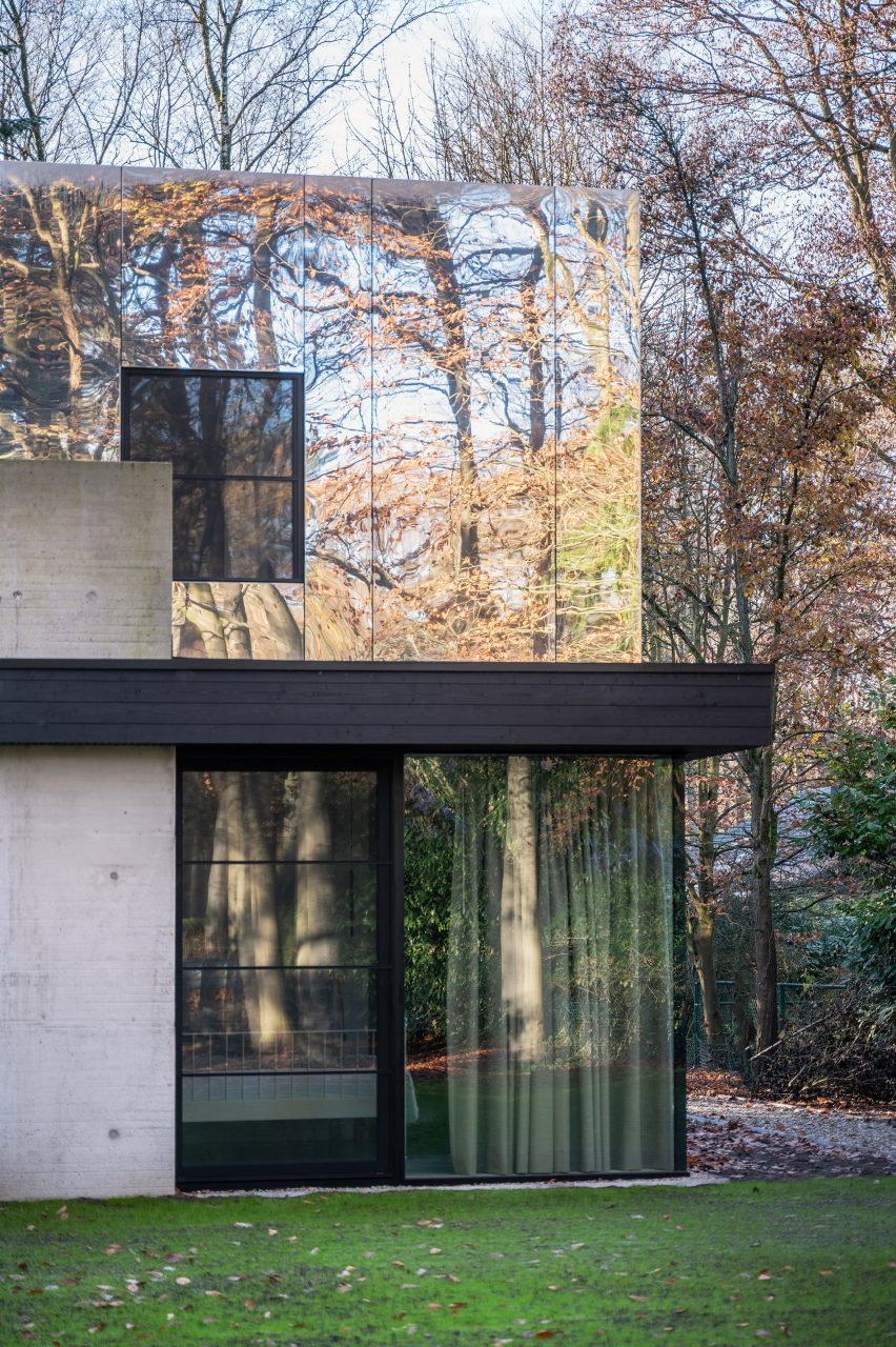 Two-storey home in a forest with a glazed ground floor and mirror-clad upper floor