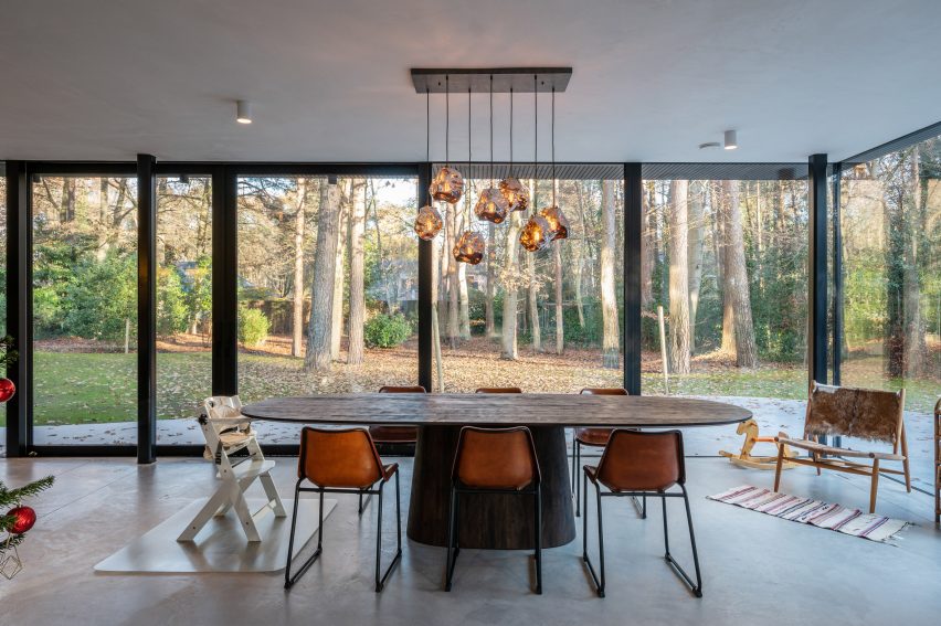 Dining area with floor-to-ceiling windows, curved table and assorted chairs