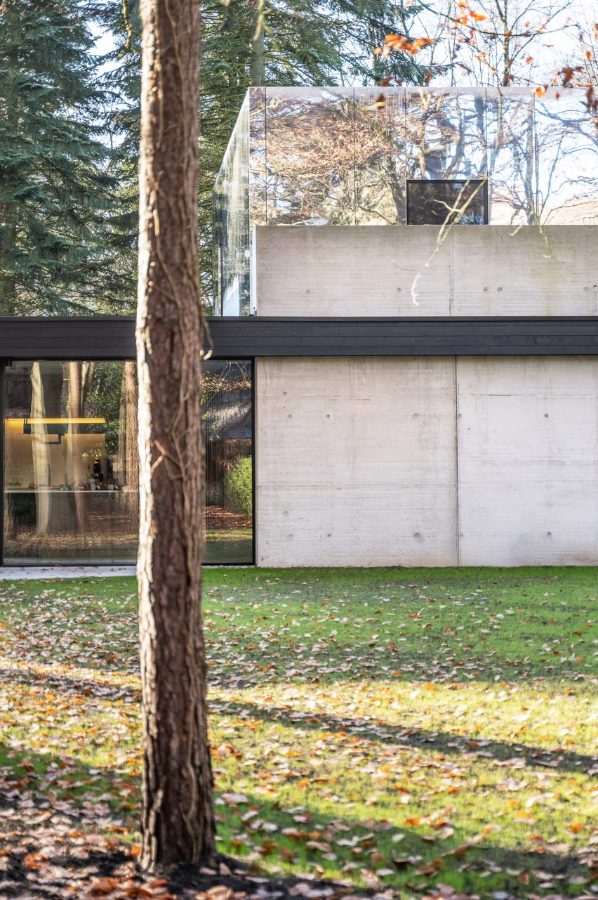 Two-storey home in a forest with concrete, glass and mirror facade