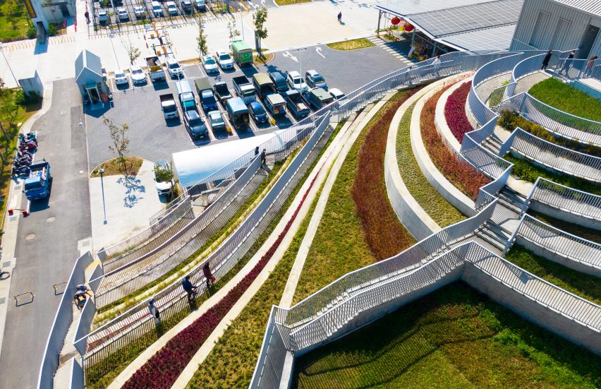 A series of stepped terraces filled with different coloured planting leading to a car park