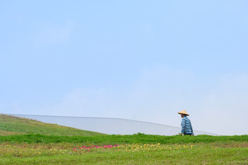 Person sitting on the undulating green roof of the Tainan food market by MVRDV