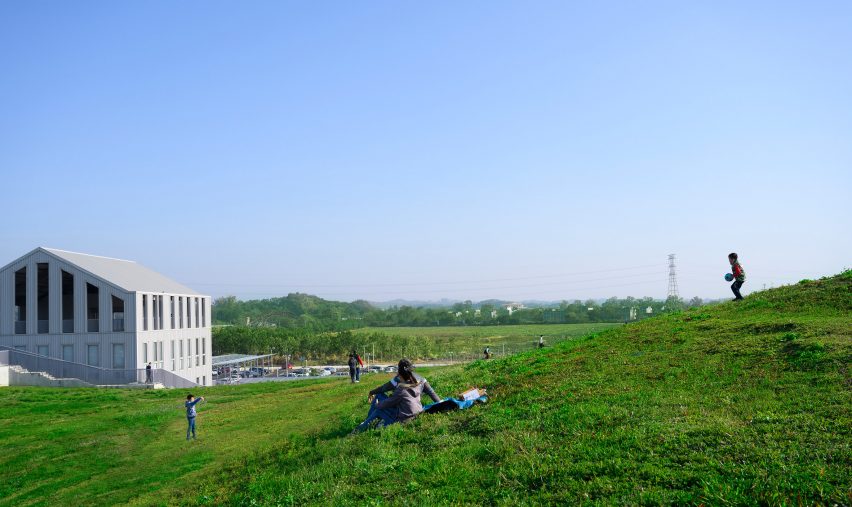 Person sitting on the undulating green roof of the Tainan food market by MVRDV