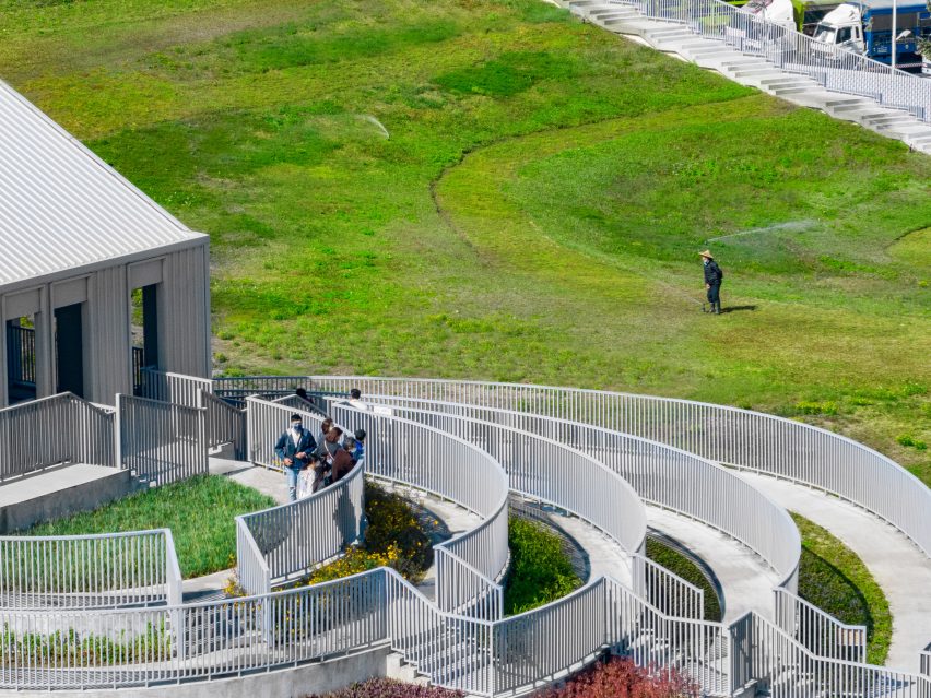 People walking on the undulating green roof and stepped terraces of the Tainan food market by MVRDV