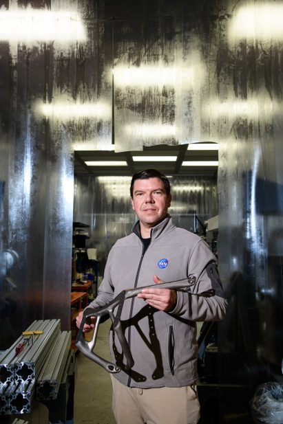 Ryan McClelland holding a an AI-designed component for astronomical instruments