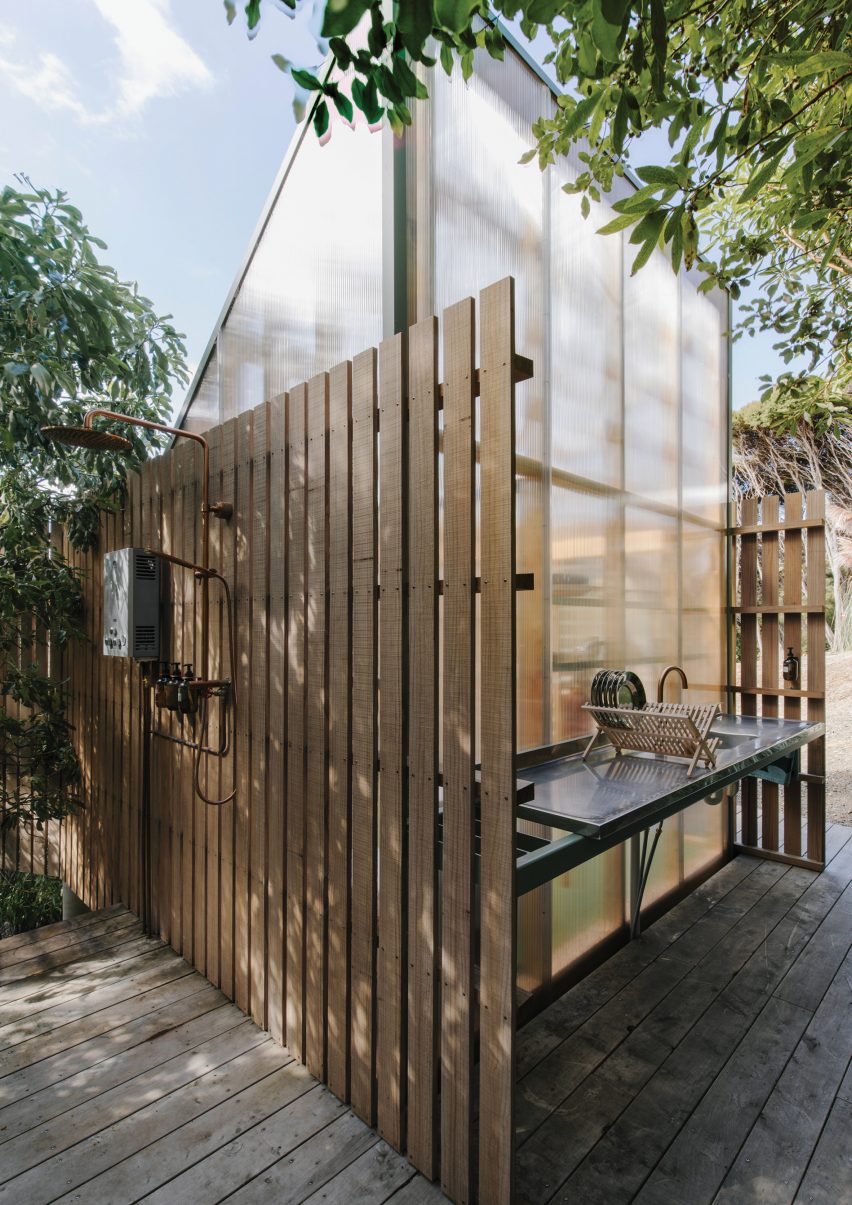 Polycarbonate mono-pitched shed covered in timber battens on a wood decking with an external sink