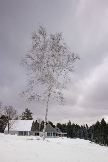 Three pitched-roof structures with granite stone walls and metal-clad gable ends on a snowy mountainside