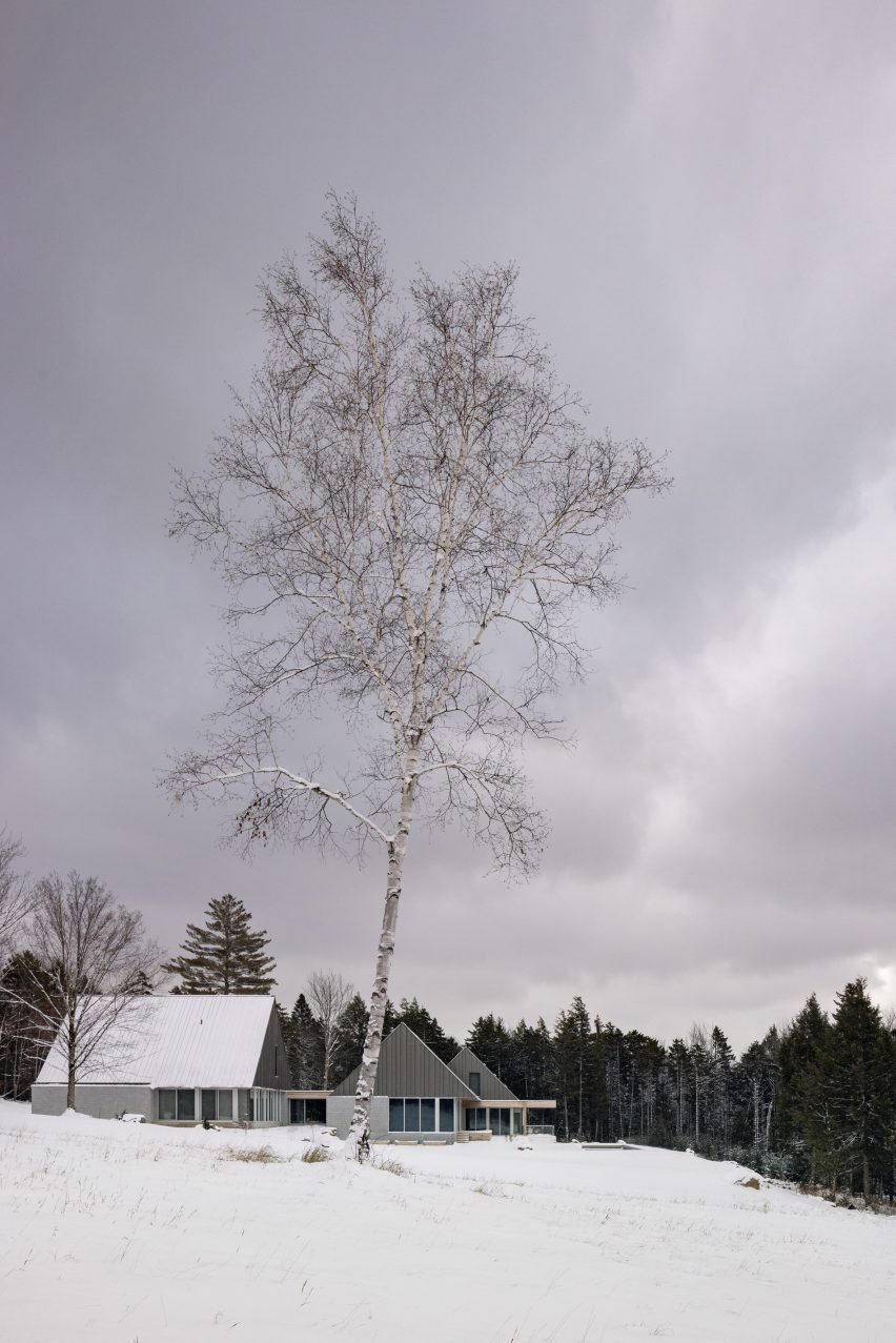 Three pitched-roof structures with granite stone walls and metal-clad gable ends on a snowy mountainside