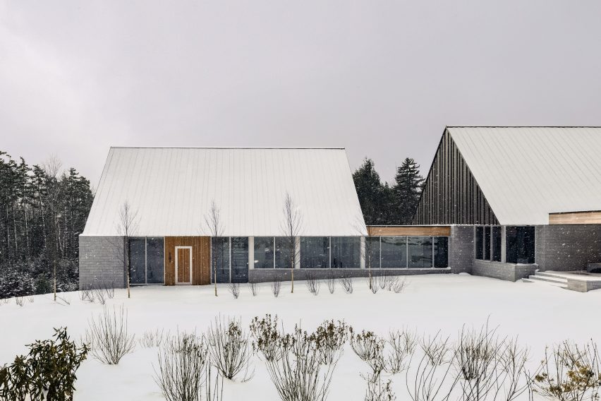 Two cabin structures with granite walls and timber panels on a snowy mountainside
