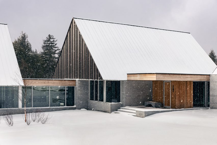 Two cabin structures with granite walls and metal-clad gable ends connected by a glazed walkway