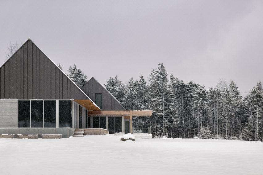 Two cabins with granite walls and metal-clad gable ends in a snowy forest