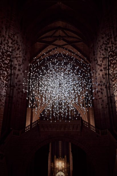 Spherical installation made up of suspended piece of coal illuminated inside a cathedral