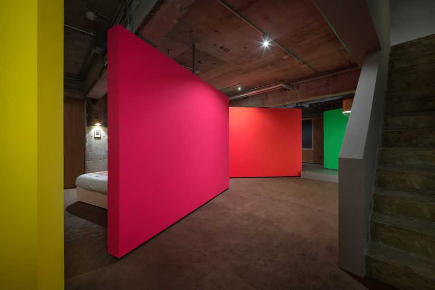 Yellow, pink, orange and green rotating partition walls zoning a bedroom in a concrete apartment
