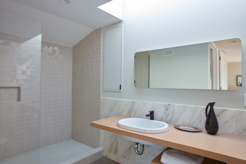 Bathroom with walk-in shower, white basin on a wood worktop and cream marble splashback