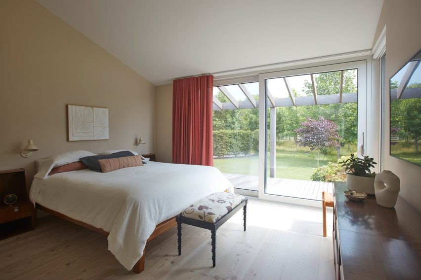 Bedroom with a double bed, ottoman, timber floors and double glass sliding doors that open to a garden