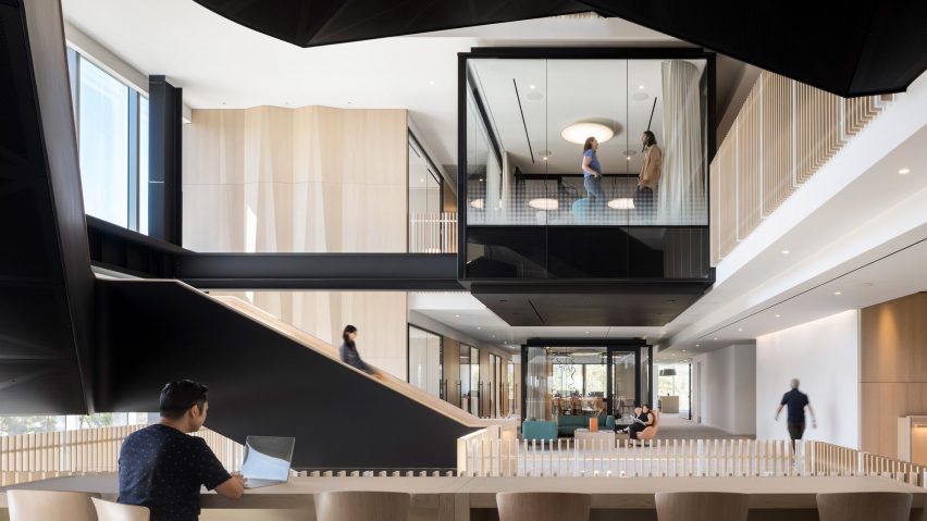 Workspaces and glass meeting rooms surround atrium