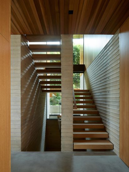 Staircase with wooden steps and scalloped concrete walls