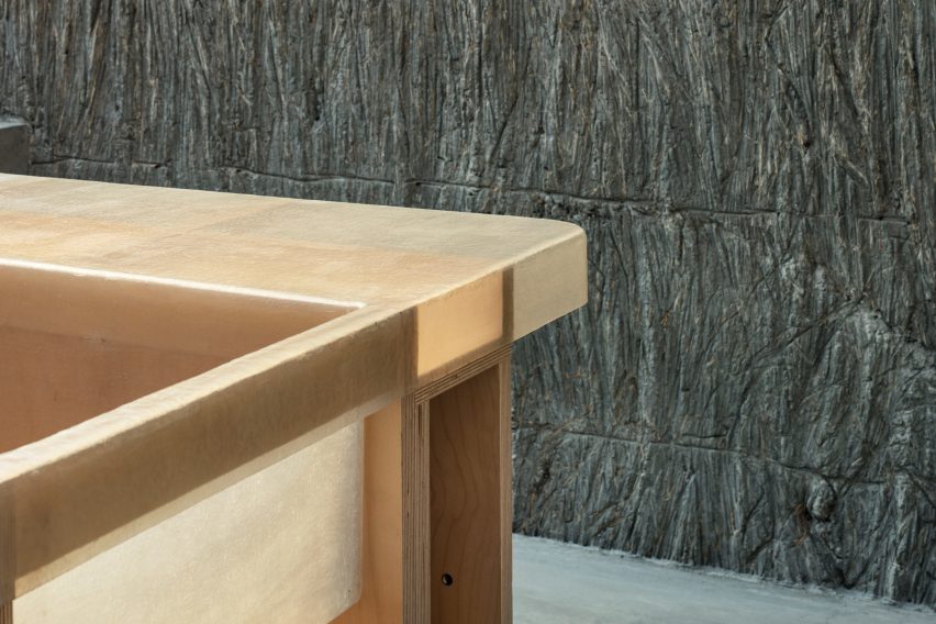 Corner of a translucent tabletop with a timber frame in a room with textured stone walls
