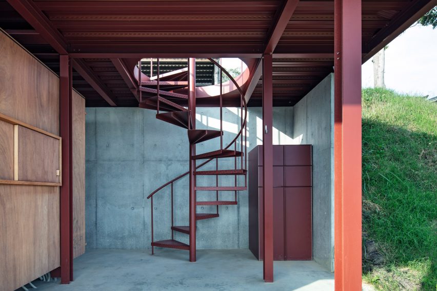Concrete room with a red steel structure and a red steel spiral staircase leading to the roof