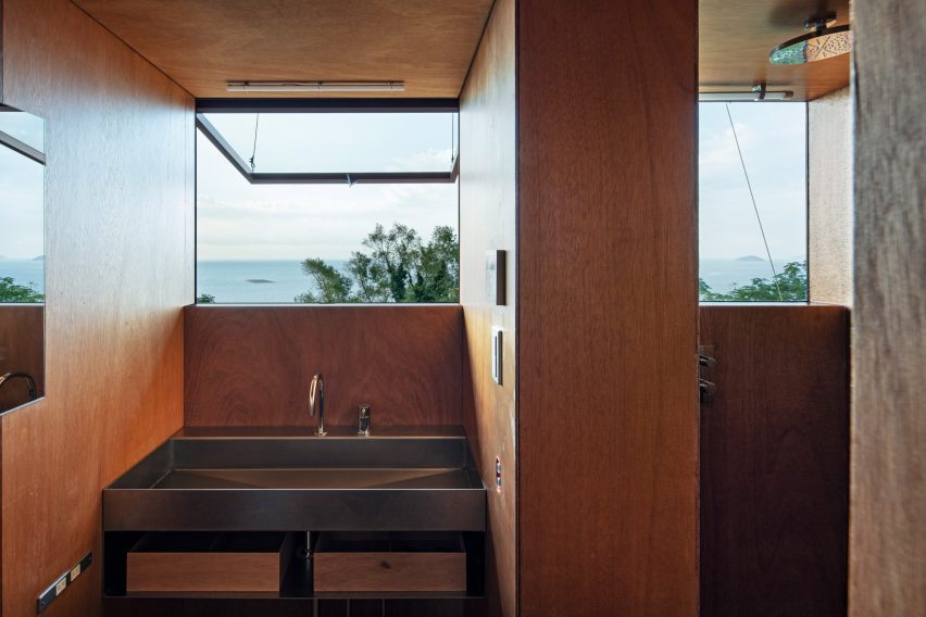 Wood-lined bathroom with a metal sink below an open window