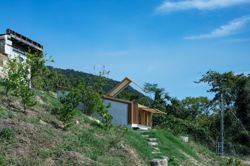 A bunker-style building with a timber-framed roof structure on a hillside in Japan