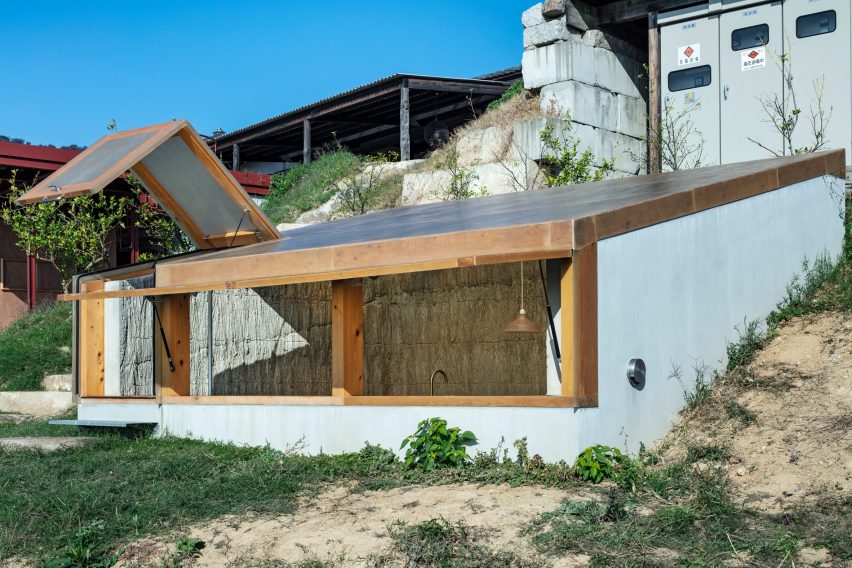 Stone bunker building with a timber-framed translucent roof on a hillside