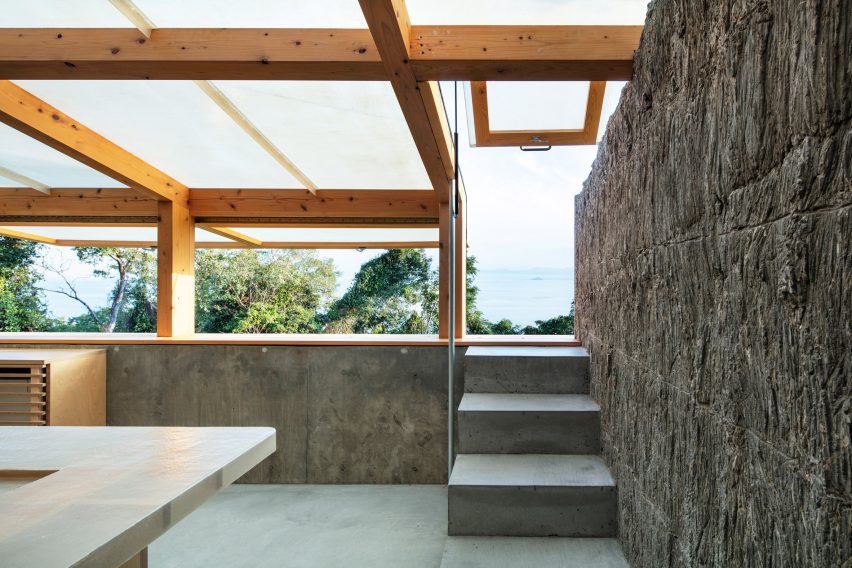 A room with textured stone walls with a translucent roof and steps leading to a window opening