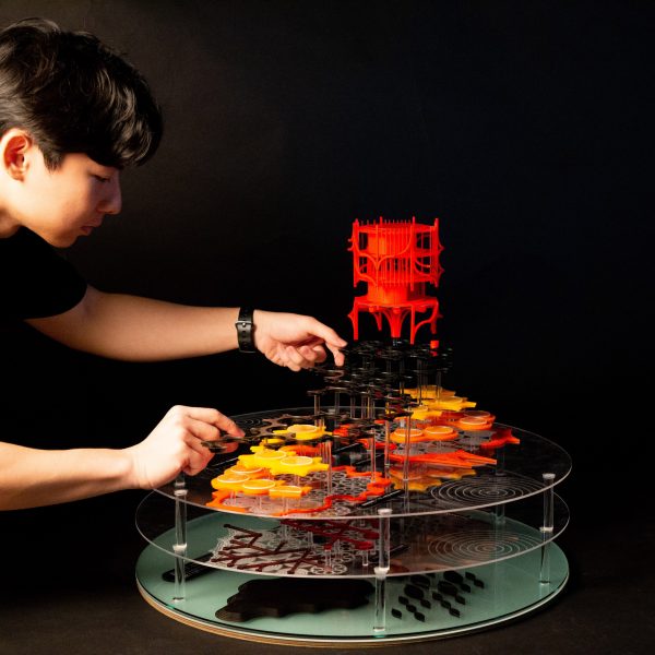 Photograph showing person adjusting multi-layered model on black backdrop