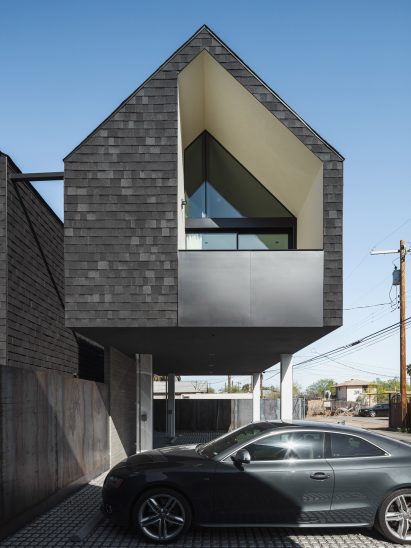 Cantilevering upper level clad in black shingles