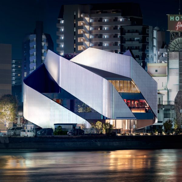 A theatre building on a city waterfront with sweeping steel panels covering the exterior