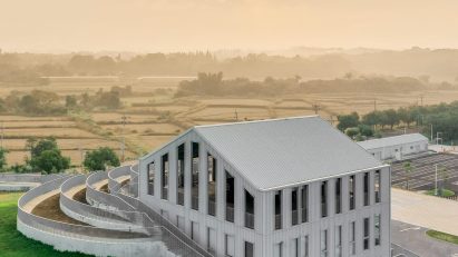 A metal-clad building with a pitched roof surrounded by a grassy mound