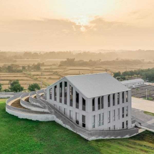 A metal-clad building with a pitched roof surrounded by a grassy mound