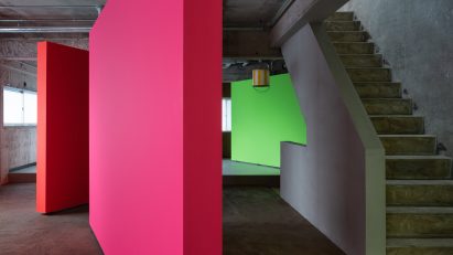 Pink, orange and green rotating partition walls in a concrete apartment by AB Rogers